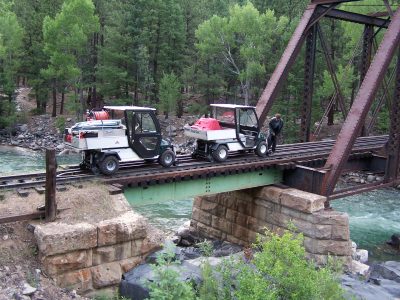 hyrailer vehicles on a bridge over a river in a forest